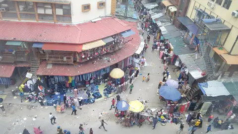 Balogun Market on Lagos Island, Nigeria, a commercial street lined with clothing stalls and shoppers.