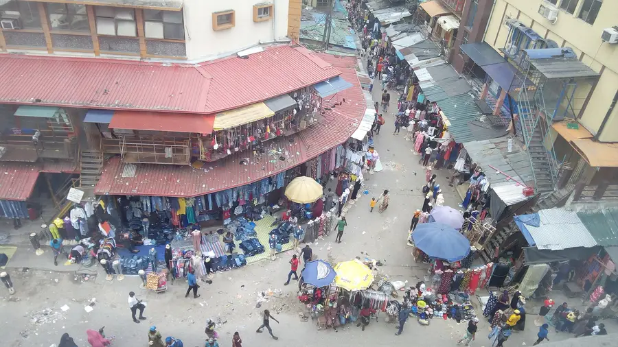 Balogun Market on Lagos Island, Nigeria, a commercial street lined with clothing stalls and shoppers.