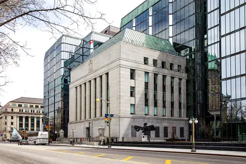 The Bank of Canada head office in Ottawa, a stone complex between glass towers, with the Canadian flag above the roof.