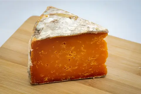 A wedge of mature cheddar on a wooden board