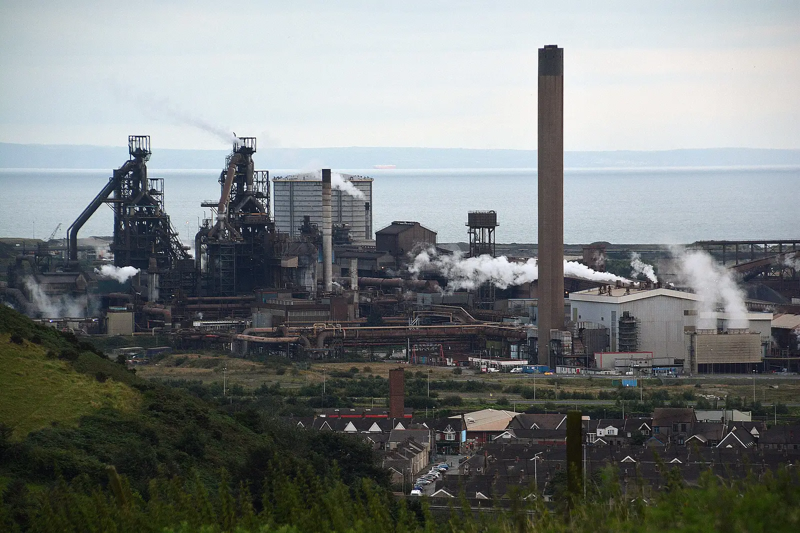 Port Talbot steelworks in Wales, with blast-furnace structures, stacks and the Bristol Channel behind the plant
