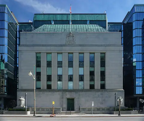 Stone facade of the Bank of Canada building on Wellington Street in Ottawa, between glass office towers