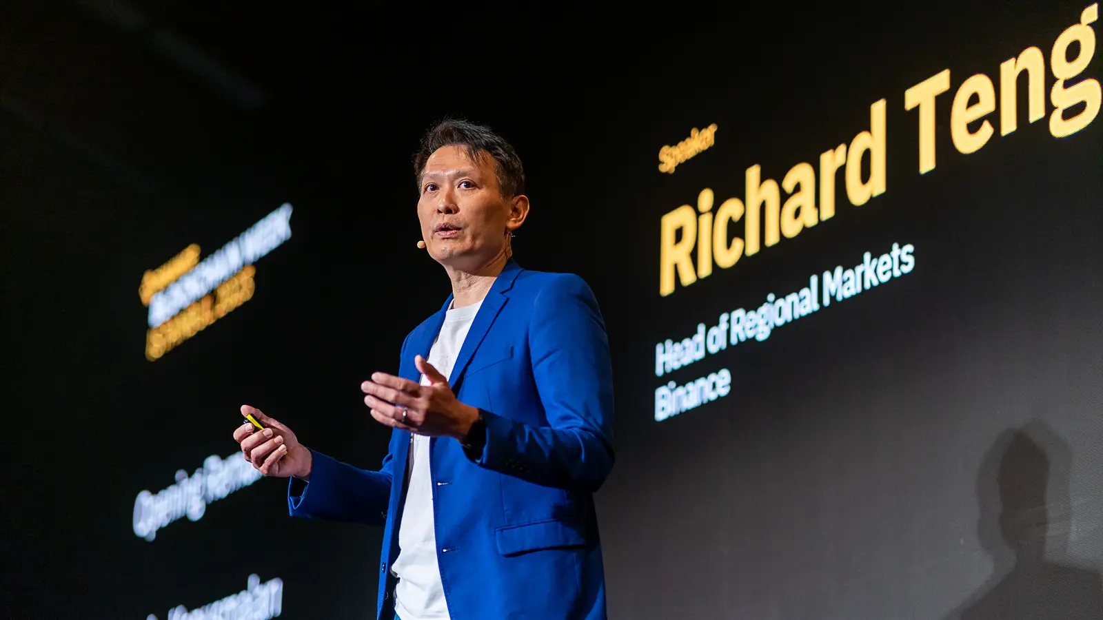 Richard Teng speaking on stage at Binance Blockchain Week 2023 in Istanbul, with his name and title projected on the screen behind him.