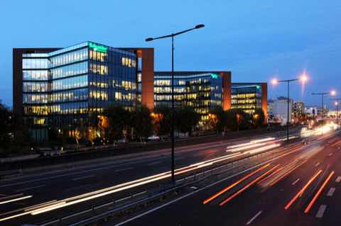 Schneider Electric headquarters at night, a glass office building beside a road