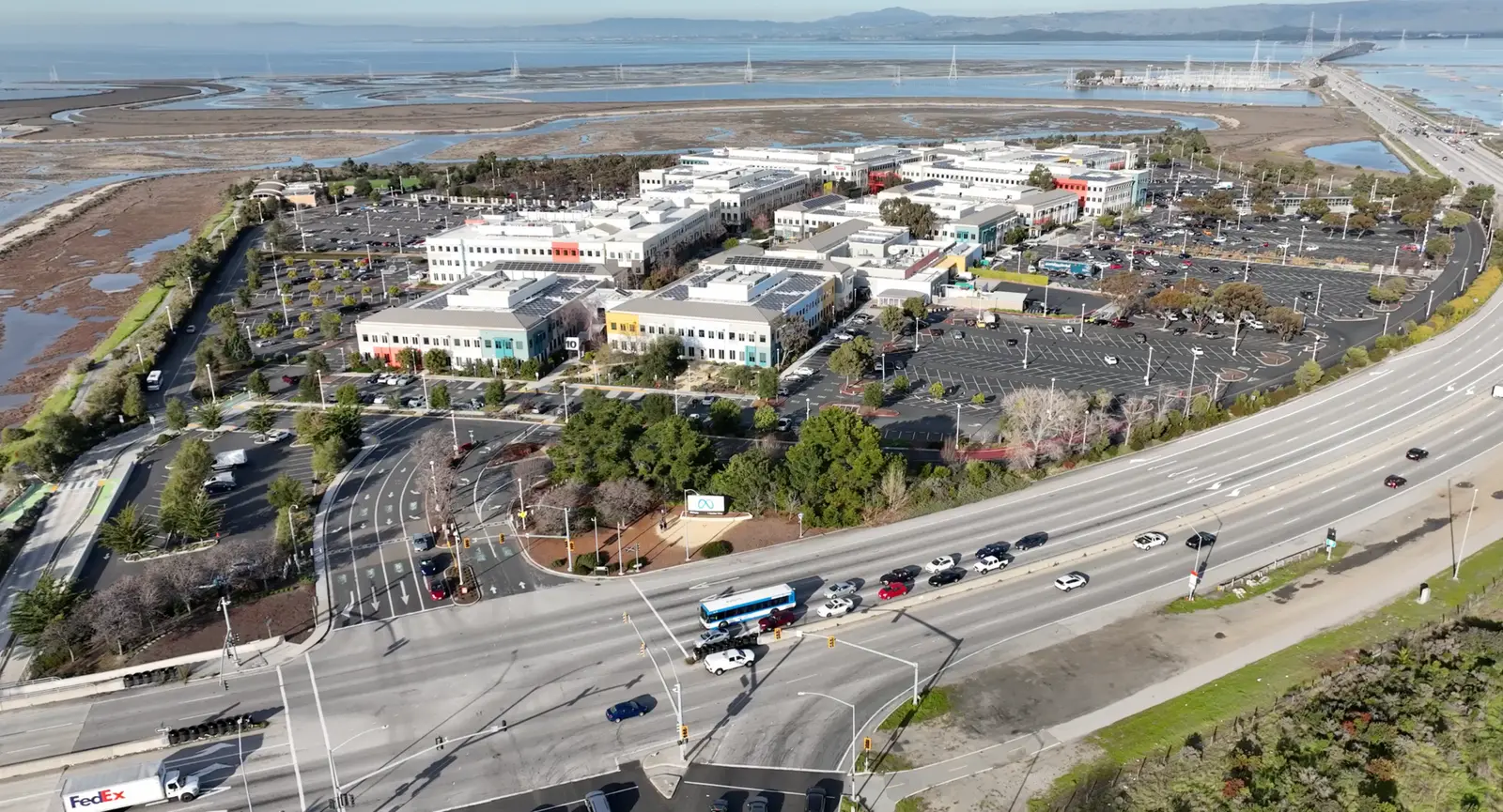 Aerial view of Meta Platforms headquarters campus at 1 Hacker Way, Menlo Park, California, with the Meta sign at the entrance and Highway 101 alongside