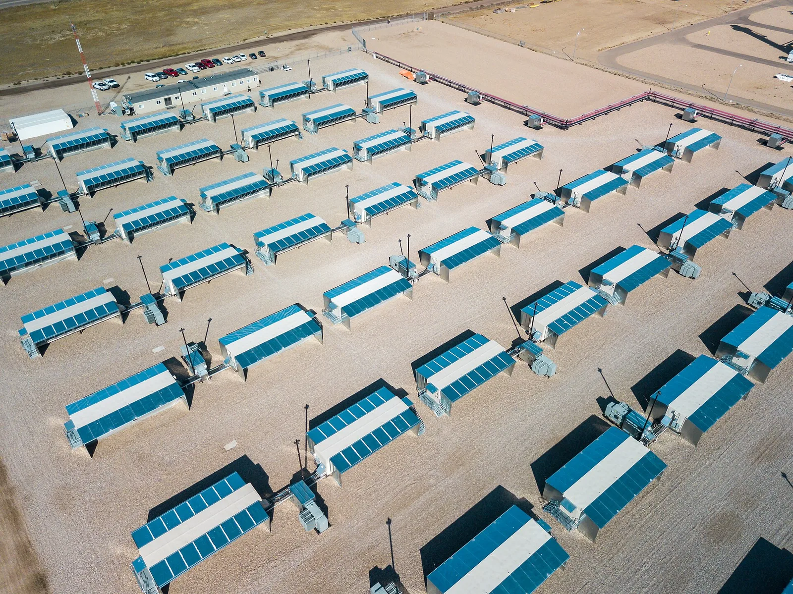 Aerial view of the Hut 8 bitcoin mining facility at Medicine Hat, Alberta, rows of blue-roofed immersion containers on a gravel pad