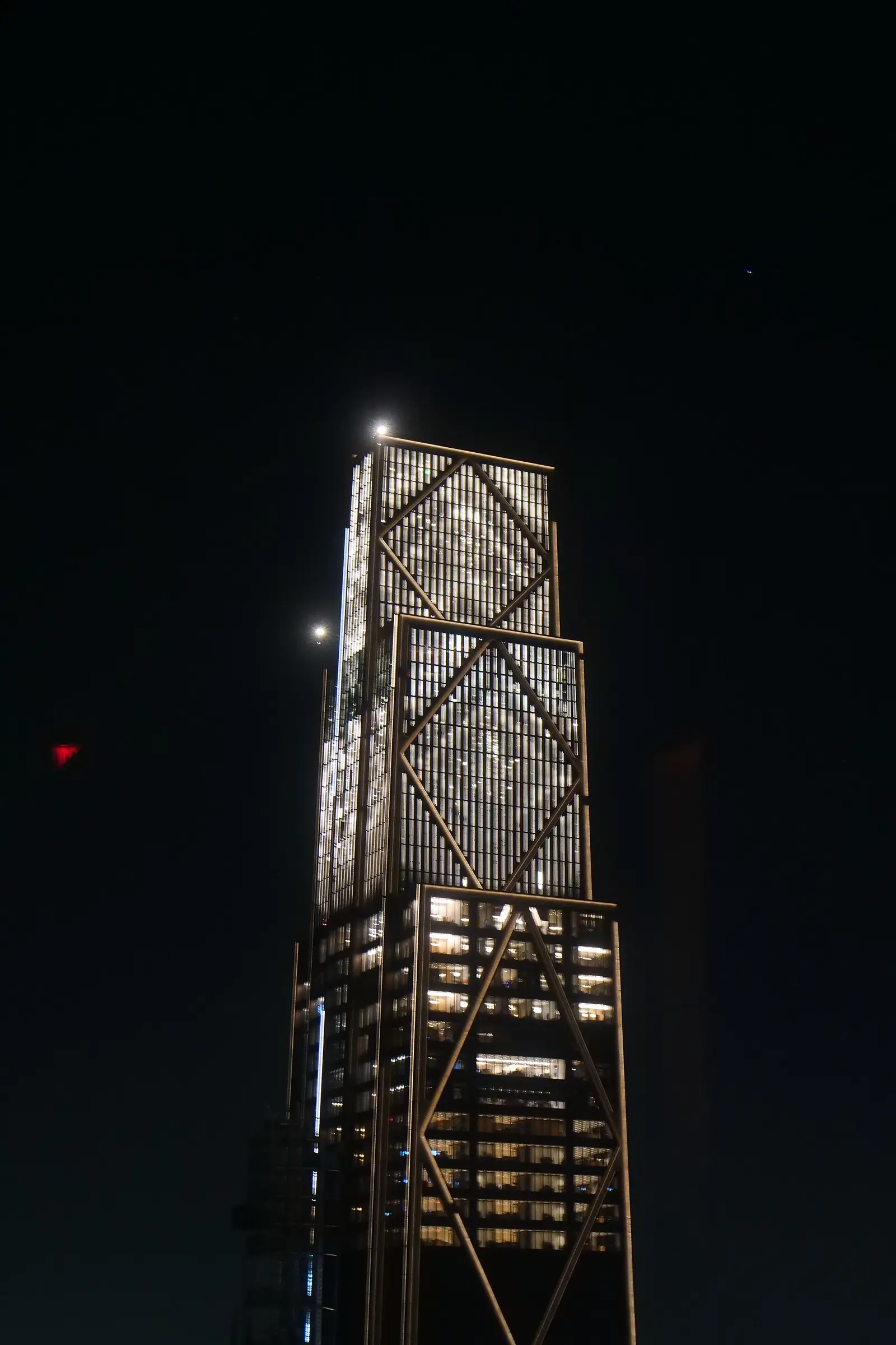 The JPMorgan Chase headquarters at 270 Park Avenue in New York at night, its diamond-braced glass facade lit against a dark sky.