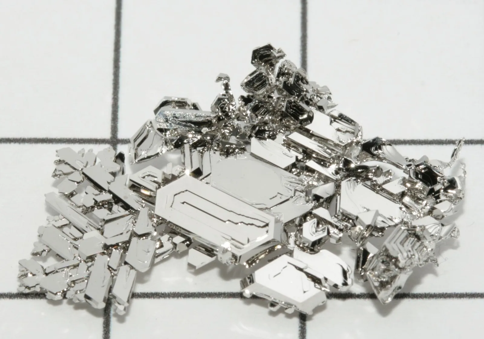 Crystals of pure platinum grown by gas phase transport, photographed on a grid background