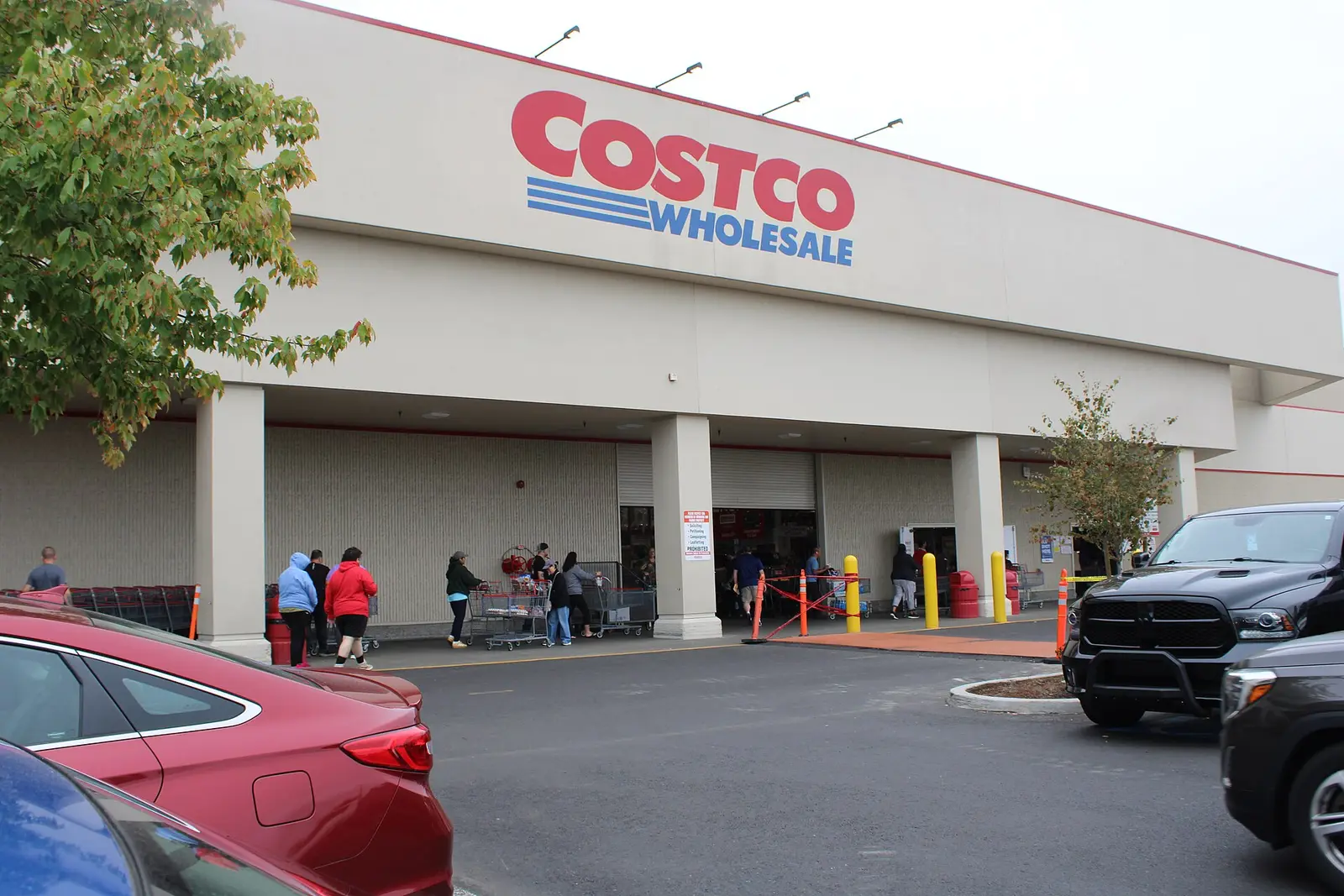 Members pushing carts outside a Costco Wholesale warehouse entrance