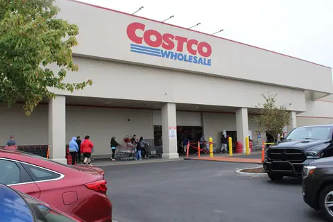 Members pushing carts outside a Costco Wholesale warehouse entrance