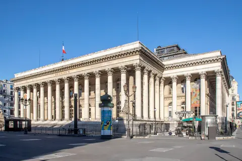 Palais Brongniart, the former Paris stock exchange building, on a sunny day with the French flag on its roof