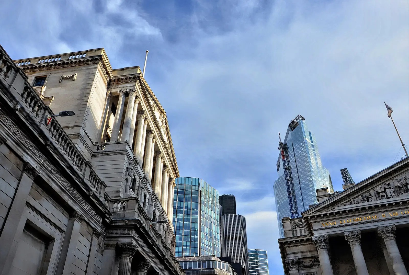 The Bank of England facade on Threadneedle Street in the City of London, with the Royal Exchange portico at right and City towers behind