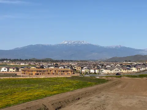 New wood-framed homes under construction beside completed tract housing in Winchester, Riverside County, California, with the San Jacinto Mountains behind