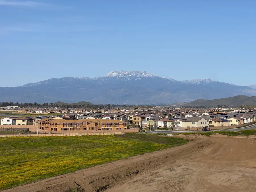 New wood-framed homes under construction beside completed tract housing in Winchester, Riverside County, California, with the San Jacinto Mountains behind