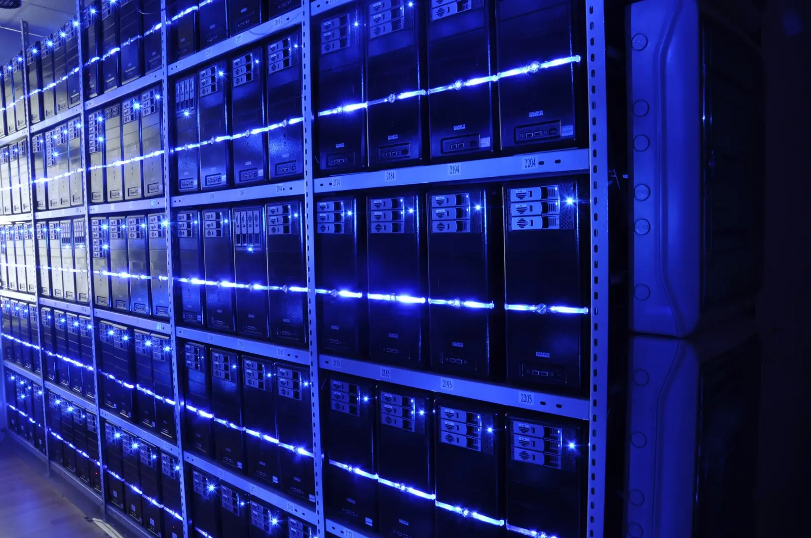 Rows of lit server towers on steel shelving inside a data centre, the kind of hardware that runs blockchain validator nodes