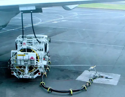 A Jet A-1 hydrant dispenser truck refuels a Boeing 777 from underground fuel pipes on an airport apron