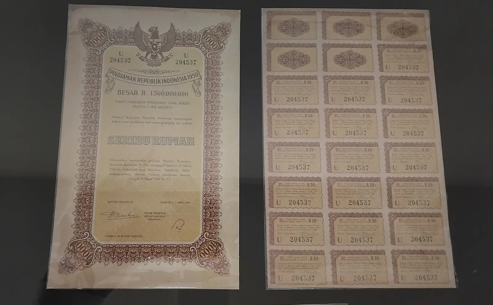 A 1950 Republic of Indonesia 1,000-rupiah bond certificate displayed beside its sheet of detachable 3 per cent interest coupons at the De Javasche Bank Museum in Surabaya
