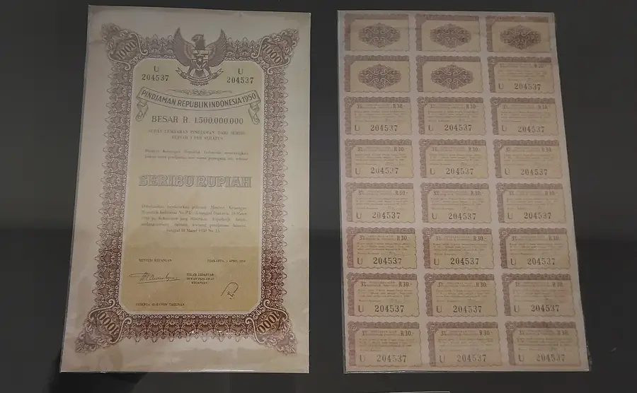 A 1950 Republic of Indonesia 1,000-rupiah bond certificate displayed beside its sheet of detachable 3 per cent interest coupons at the De Javasche Bank Museum in Surabaya