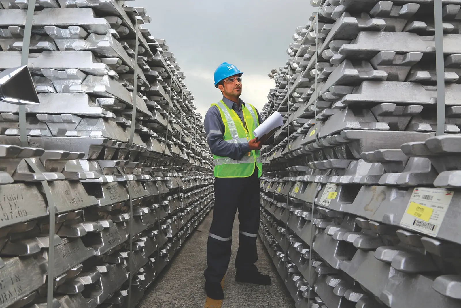 A worker inspects stacked primary aluminium ingots in the storage yard of the Aluminium Bahrain (Alba) smelter