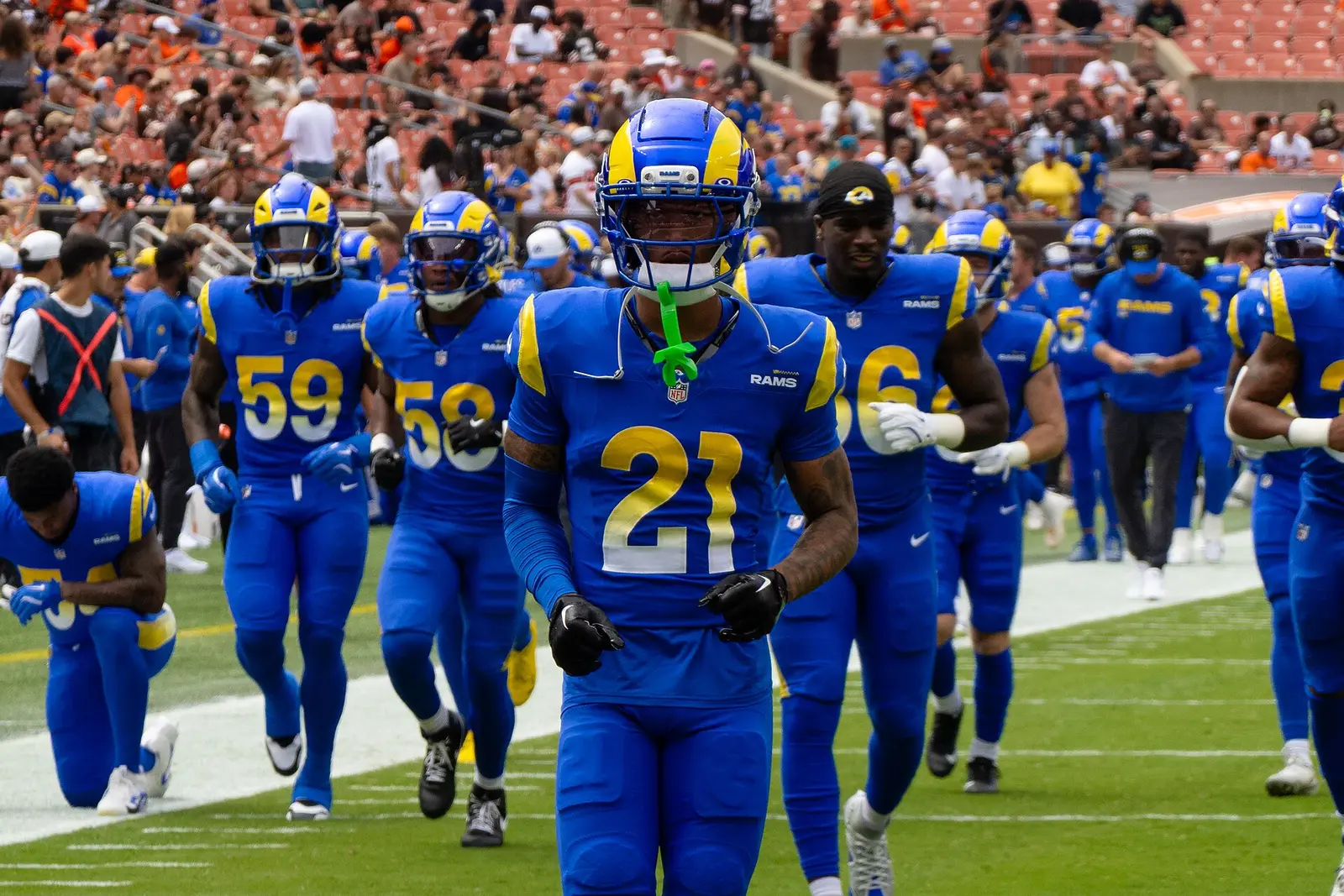 Los Angeles Rams players in royal and gold uniforms jogging onto the field before a game