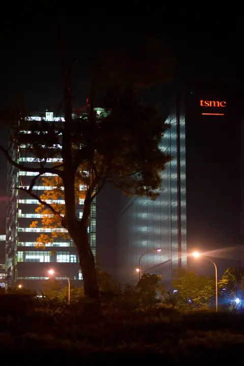 Night photograph of TSMC buildings at the Hsinchu Science Park, with the company sign lit on the tower