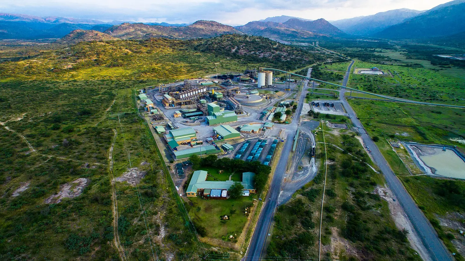 Aerial view of the Two Rivers platinum mine in South Africa, with plant buildings, silos and a conveyor among bushveld hills