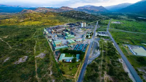 Aerial view of the Two Rivers platinum mine in South Africa, with plant buildings, silos and a conveyor among bushveld hills