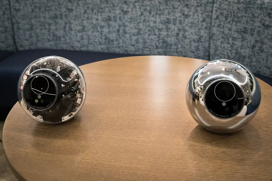 Two Tools for Humanity Orbs, one clear-cased and one chrome, on a table at a TechCrunch event in January 2024.